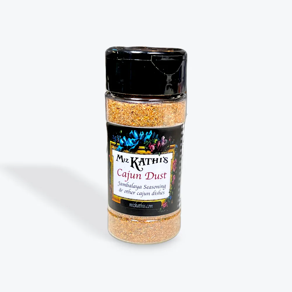 A shaker jar of Miz Kathi’s Cajun Dust, the jambalaya seasoning, with a black lid and the house floral label